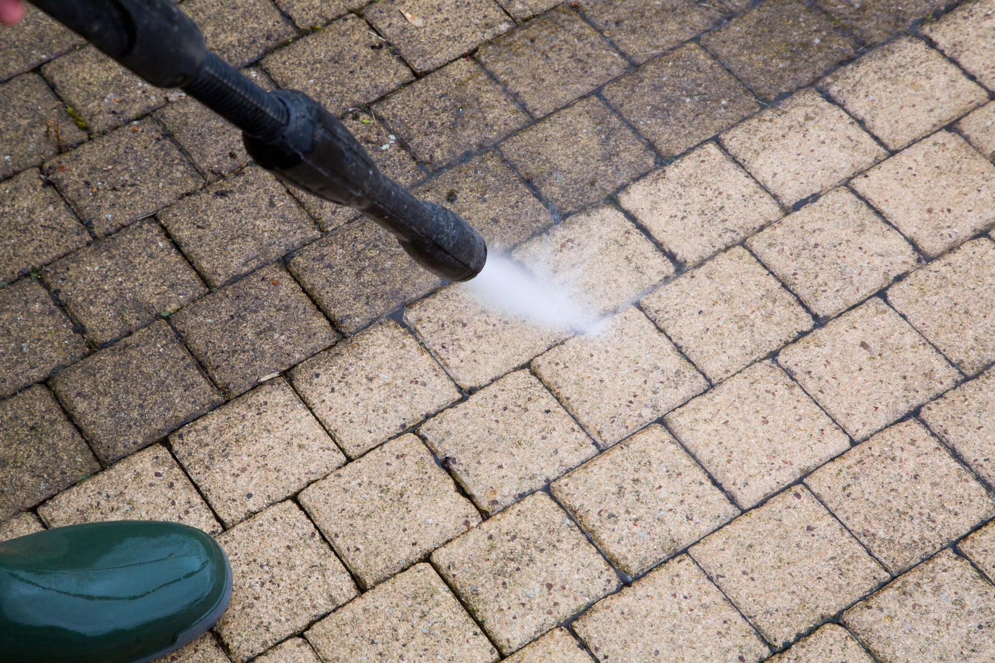 Man pressure washing some block paving patio